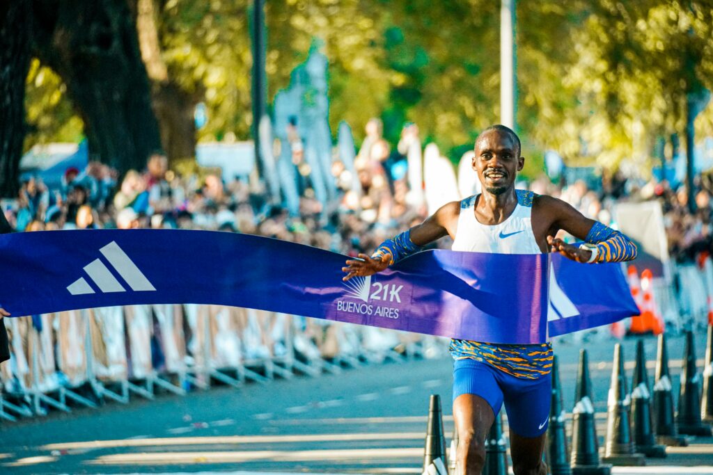 Male athlete crossing the finish line at the Buenos Aires marathon in a lively outdoor event.